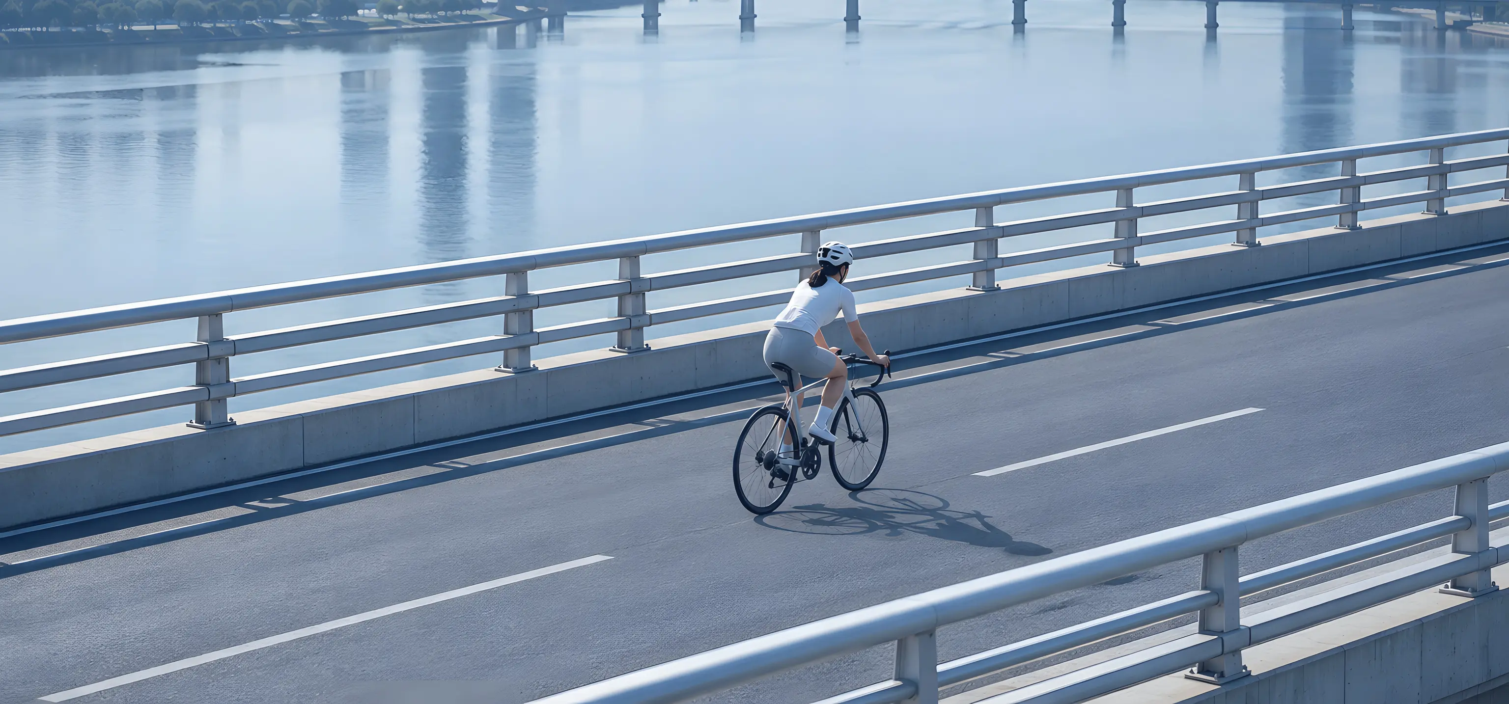 A cyclist crossing a city bridge at dawn
